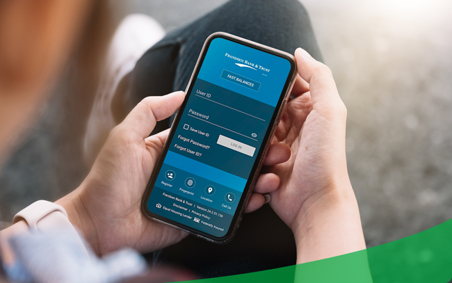 Close-up of a person holding a smartphone and logging into the Frandsen Bank & Trust mobile app—illustrating secure, convenient access to checking and savings accounts anytime, anywhere.